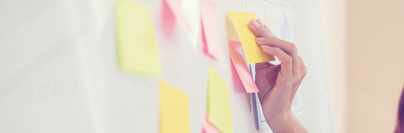 Post-Its werden auf eine Flipchart geklebt.