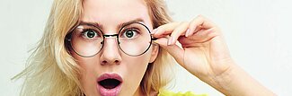 überraschte junge blonde Frau mit Brille