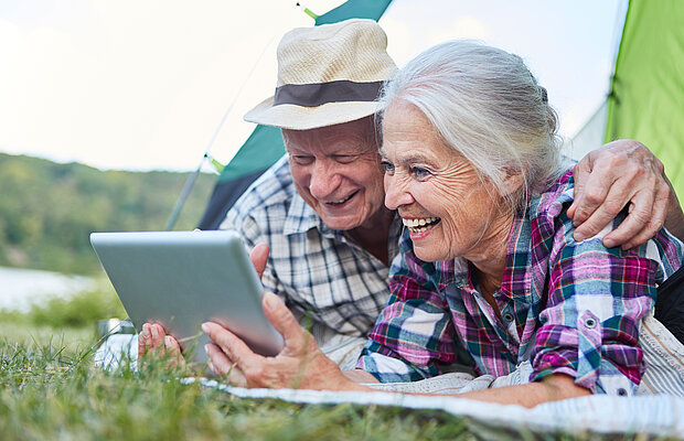 Senioren schauen auf Tablet.