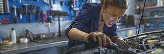 Blonde junge Frau repariert ein Auto in einer Werkstatt